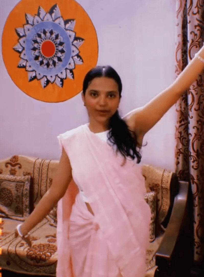 Shivangi in a pink sari with arms spread out