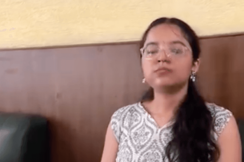 Shivangi at a café in a white patterned sleeveless top and clear glasses, calm and smiling